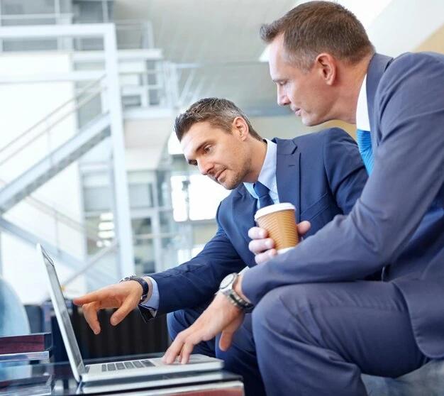 two-businessmen-discussing-content-strategy-while-working-on-laptop-in-office-space